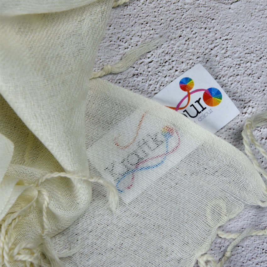 Merino wool twill shawl tassel detail with colourful tag on cream fabric