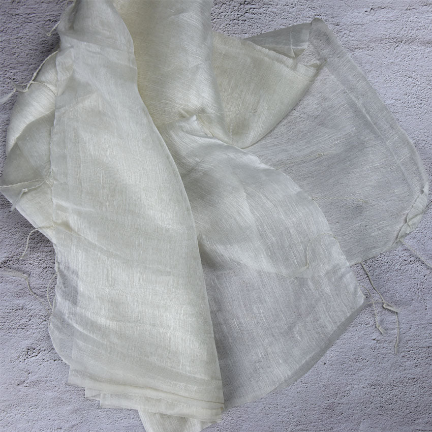 Sheer silk linen fabric in off-white, draped with tasseled edges