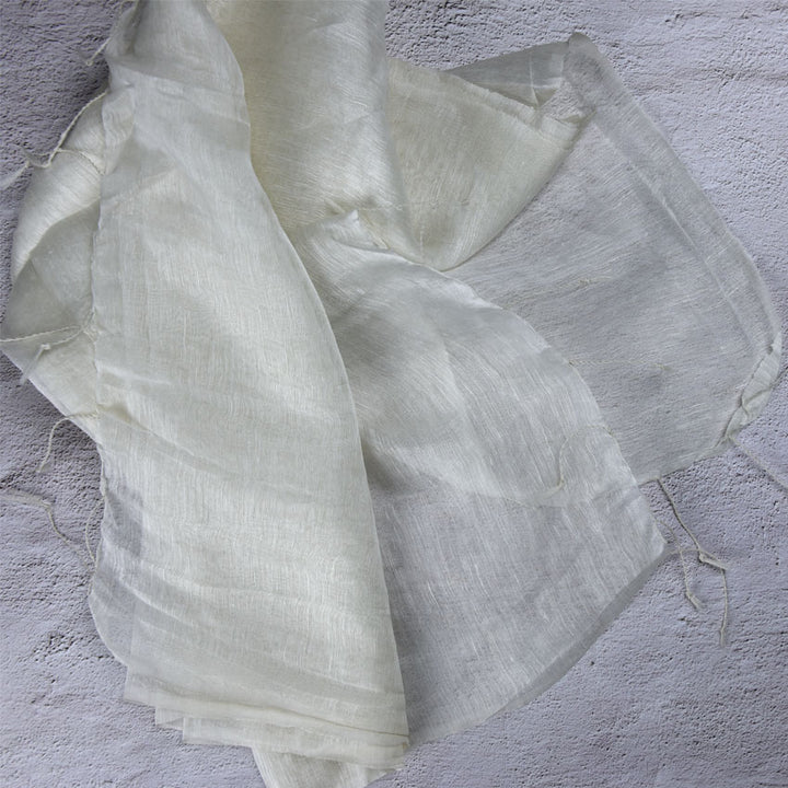 Sheer silk linen fabric in off-white, draped with tasseled edges